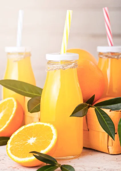 Glasflaschen Mit Frischem Bio Orangensaft Mit Rohen Orangen Auf Hellem — Stockfoto