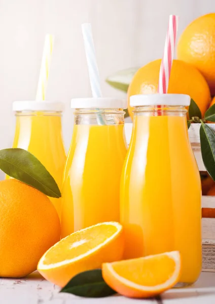玻璃瓶有机新鲜橙汁与生橙子在白色木箱 — 图库照片