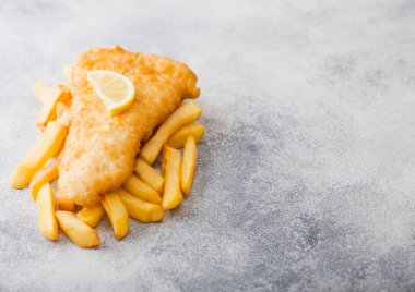 Geleneksel İngiliz balık ve cips limon dilim beyaz taş ile arka plan masa. Metin için yer