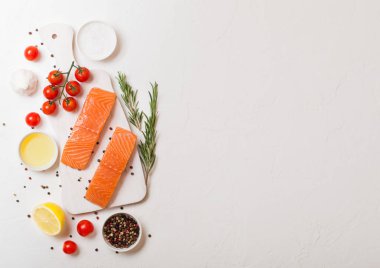 Taze Çiğ somon dilimi Kıyma Kurulu petrol domates ve limon ile taş mutfak masa arka plan üzerinde üzerinde. Metin için yer. Biberiye ve tuz ile