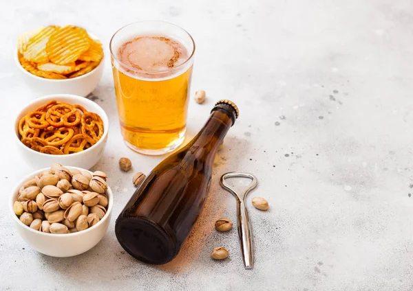 Glas en fles van ambachtelijke pils met snack en opener op st — Stockfoto