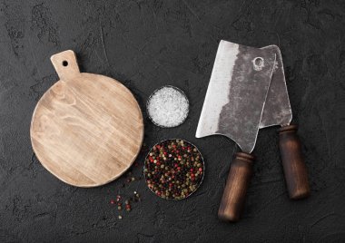 Vintage et bıçağı baltaları vintage doğrama tahtası ve siyah tablo arka plan ile. Kasap kaplar. Yakın çekim. Tuz ve biber