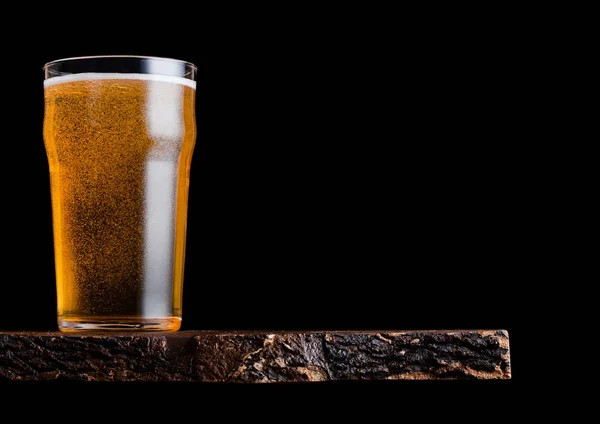 Glass of lager beer with foam and bubbles on vintage wooden board on black background. Space for text — Stock Photo, Image