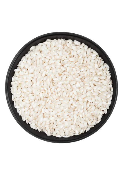 Black bowl of raw organic arborio risotto rice on white background. Healthy food. — Stock Photo, Image