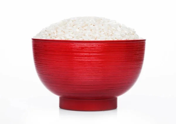 Red bowl of raw organic arborio risotto rice on white background. Healthy food. — Stock Photo, Image