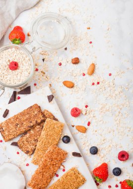 Organik tahıl granola bar tatlım kaşık ve yulaf ve keten havlu mermer zemin üzerine kavanoz ile mermer gemide çilek ile. 