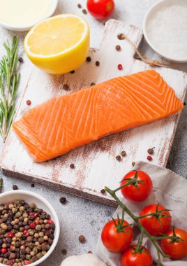 Taze Çiğ somon dilimi Kıyma Kurulu petrol domates ve limon ile taş mutfak masa arka plan üzerinde üzerinde. Biberiye ve tuz ile