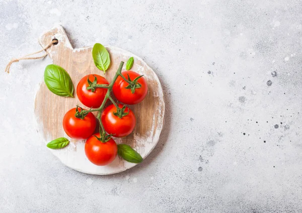 Tomates cereja orgânicos na videira com manjericão e pimenta em tábua de cortar no fundo da cozinha de pedra. Espaço para texto — Fotografia de Stock