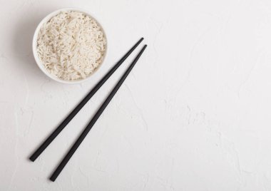 Beyaz arka planda siyah Chopsticks ile haşlanmış organik Basmati Yasemin pirinç ile beyaz kase. Metin alanı