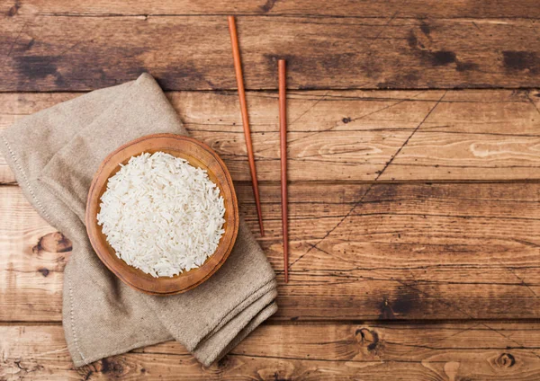 Cuenco de madera con arroz jazmín basmati orgánico hervido y palillos de madera con toalla de lino sobre fondo de madera antiguo.Espacio para texto —  Fotos de Stock