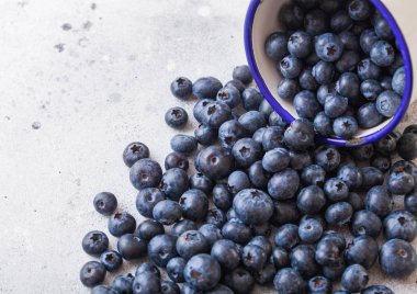 Beyaz arka planda emaye beyaz bardak yaprak ile taze ham organik yaban mersini. Vintage gıda fotoğraf