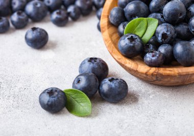 Beyaz arka planda ahşap kase yaprak ile taze ham organik yaban mersini. Makro