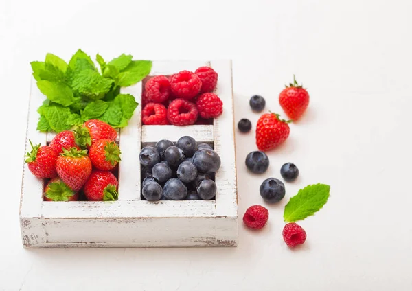 Fresh raw organic berries in white wooden box on white kitchen table background. Top view. Strawberry, Raspberry, Blueberry and Mint leaf — Stock Photo, Image