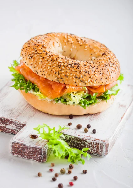 Sanduíche de bagel saudável fresco com salmão, ricota e alface na tábua de corte vintage no fundo da mesa da cozinha branca. Alimentação saudável . — Fotografia de Stock
