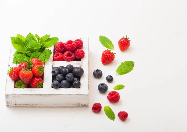 Fresh raw organic berries in white wooden box on white kitchen table background. Space for text. Top view. Strawberry, Raspberry, Blueberry and Mint leaf — Stock Photo, Image