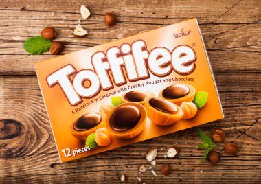 Londra, İngiltere - 15 Nisan 2019: Ahşap zemin üzerinde tonlu ve fındıklı Toffifee şekerkutusu. Kremsi Nougat ve çikolata ile Karamel bir fındık.