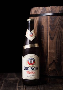 LONDON, UK - JULY 28, 2018: Bottle of Erdinger wheat beer next to wooden barrel.Erdinger is the product of the world's largest wheat beer brewery. clipart