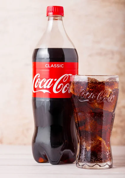 ЛОНДОН, Великобритания - 03 августа 2018 года: Пластиковая бутылка и оригинальный стакан оригинального безалкогольного напитка Coca Cola на деревянном фоне. Самый популярный напиток в мире . — стоковое фото