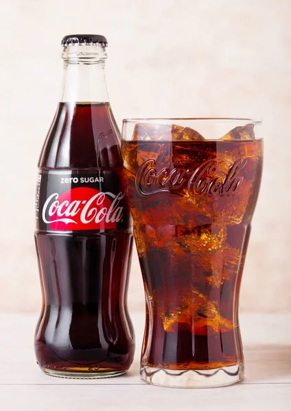 ЛОНДОН, Великобритания - 03 августа 2018 года: Стеклянная бутылка и оригинальный стакан безалкогольного напитка Zero Sugar Coca Cola на деревянном фоне. Самый популярный напиток в мире — стоковое фото