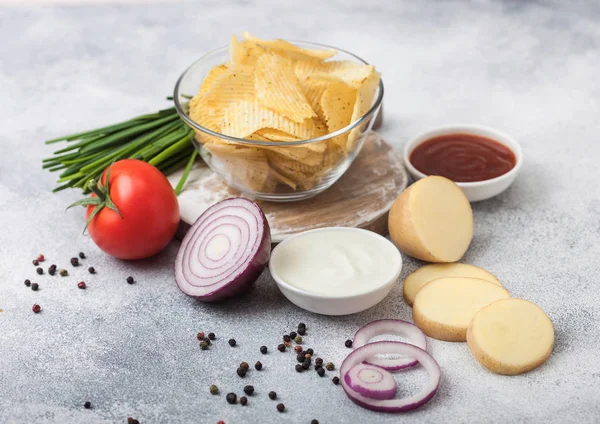 Patatas fritas frescas orgánicas hechas en casa en un tazón de vidrio con crema agria y cebollas rojas sobre un fondo de mesa de cocina claro. Tomate con ketchup y cebolla verde — Foto de Stock