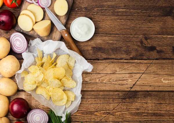 Patatas fritas frescas orgánicas caseras con crema agria y cebollas rojas y especias sobre fondo de mesa de madera.Espacio para texto — Foto de Stock