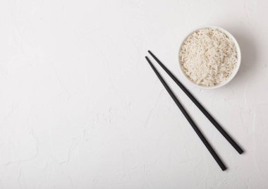 Beyaz arka planda siyah Chopsticks ile haşlanmış organik Basmati Yasemin pirinç ile beyaz kase. Metin alanı