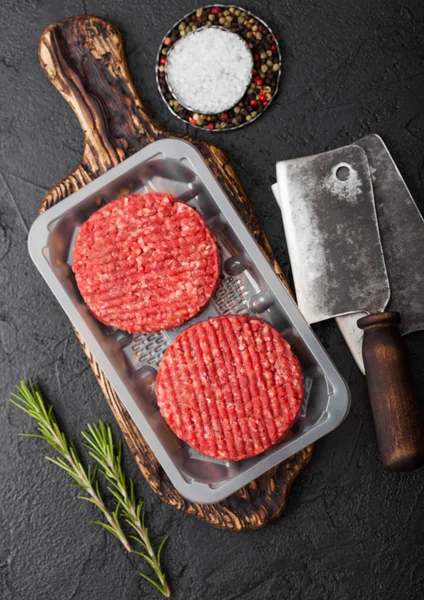 Plateau en plastique avec crus hachés fermiers maison griller burgers de bœuf avec des épices et des herbes et des hachettes de viande sur noir . — Photo