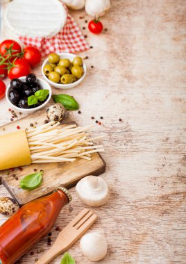 Ahşap arka plan üzerinde domates sosu ve peynir şişesi ile bıldırcın yumurtası ile ev yapımı spagetti makarna. Klasik İtalyan köy yemekleri. Sarımsak, champignons, siyah ve yeşil zeytin, yağ ve spatula.