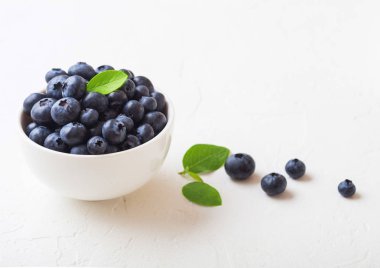 Beyaz arka plan üzerinde beyaz çin kase yaprak ile Taze ham organik yaban mersini. Makro yakın çekim