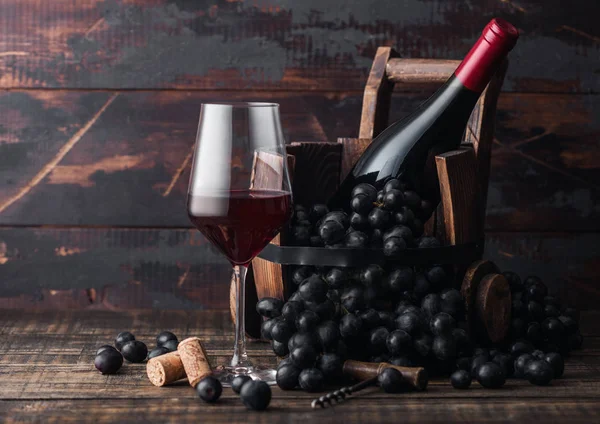 Elegant glass of red wine with dark grapes and bottle of wine in Stock Picture