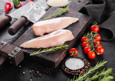 Taze ham organik tavuk fileto meme ahşap arka planda otlar ile et dülger baltaları ve baharatlar ile Vintage tahta üzerinde. Domates ve biber.