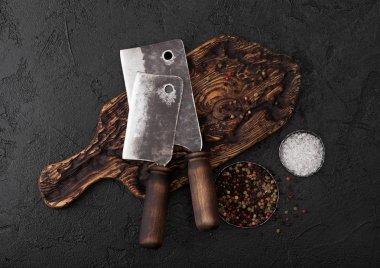 Klasik doğrama tahtası ve siyah taş masa artalanını Vintage et bıçağı balta. Kasap kaplar. Tuz ve biber.