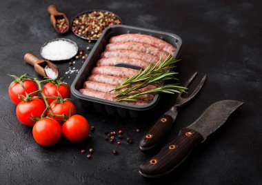 Ham sığır eti ve domuz sosis vintage bıçak ve çatal siyah arka plan üzerine plastik tepsi. Tuz ve karabiber biberiye ve domates ile.