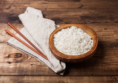 Eski ahşap arka planda keten havlu ile haşlanmış organik Basmati Yasemin pirinç ve ahşap Chopsticks ile ahşap kase.