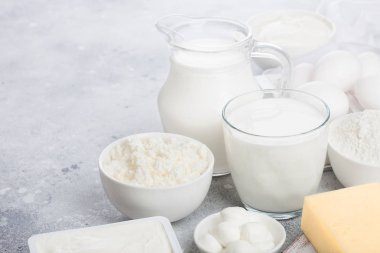 Beyaz masa arka planda taze süt ürünleri. Kavanoz ve süt bardak, ekşi krema kase, süzme peynir ve kabartma un ve mozzarella. Yumurta ve peynir. Metin için alan