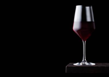 Siyah arka plan üzerinde ahşap tahta üzerinde kırmızı şarap bir bardak. Metin için alan