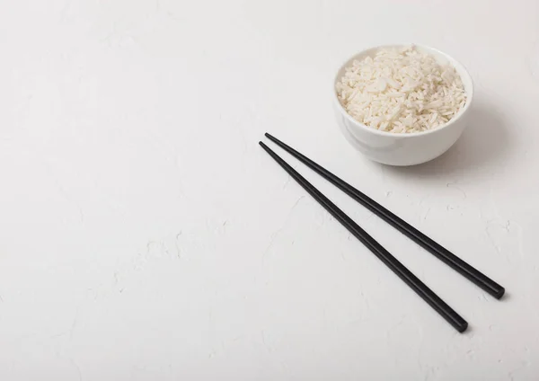 Cuenco blanco con arroz jazmín basmati orgánico hervido con palillos negros sobre fondo blanco. Espacio para texto —  Fotos de Stock