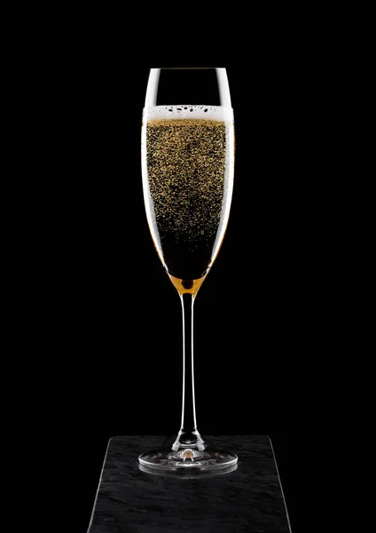 Copo elegante de champanhe amarelo com bolhas na placa de mármore blavk no fundo preto . — Fotografia de Stock