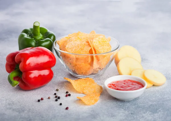 Glass bowl plate with potato crisps chips with paprika on light table background. Red and green paprika pepper with potatoes and sweet chilli sauce. — Stock Photo, Image