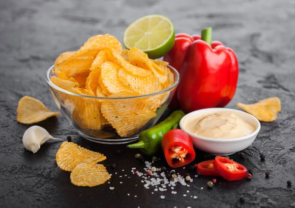 Placa de vidrio con papas fritas con pimentón y chiles sobre fondo de mesa de piedra negra. Pimentón rojo con limón y salsa picante picante . — Foto de Stock