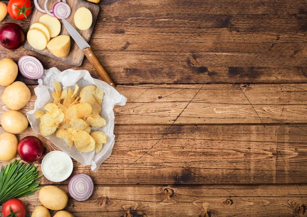 Patatas fritas frescas orgánicas caseras con crema agria y cebollas rojas y especias sobre fondo de mesa de madera.Espacio para texto — Foto de Stock