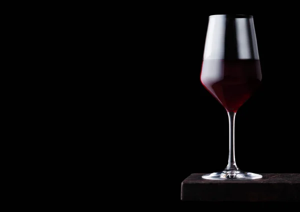 Verre de vin rouge sur planche de bois sur fond noir. Espace pour le texte — Photo