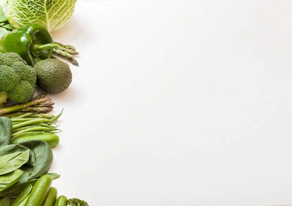 Verdure biologiche crude di colore verde assortite su fondo bianco. Avocado, cavolo, broccoli, cavolfiore e cetriolo con fagioli tagliati e mung, pak choi, pepe sciolto e lattuga. Spazio per testo Foto Stock Royalty Free