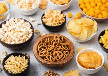 Fıstık, patlamış mısır ve soğan halkaları ve hafif arka planda kase plakaları tuzlu kraker ile tüm klasik patates atıştırmalıkları. Cips ve patates cipsi, nachos ve peynir topları ile cipsler ile Twirls.