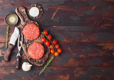Taze ham kıyılmış ev yapımı çiftçiler baharat ve otlar ve ahşap tahta üzerinde bıçak ile çatal ile Vintage Doğrama Kurulu üzerinde sığır Burger ızgara. Yağ, sarımsak ve domates.
