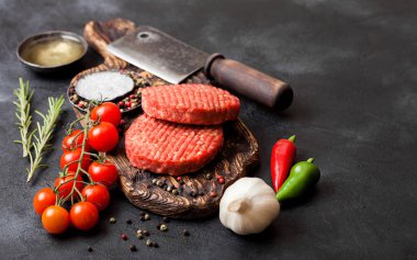 Taze ham kıyılmış ev yapımı çiftçiler baharat ve otlar ve siyah tahta üzerinde et balta ile Vintage Doğrama Kurulu üzerinde sığır Burger ızgara. Yağ, sarımsak ve domates.