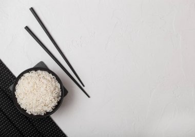 Kaynamış organik basmati yasemin pilavı ile beyaz arka planda bambu servis paspası üzerinde siyah çubuklarla beyaz kase. Metin için boşluk