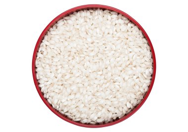 Red bowl of raw organic arborio risotto rice on white background. Healthy food.  clipart