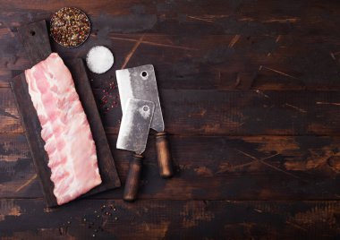 Tahta üzerinde taze ham domuz kaburga ve ahşap arka plan üzerinde vintage baltalar. Biber ve tuz. Metin için alan