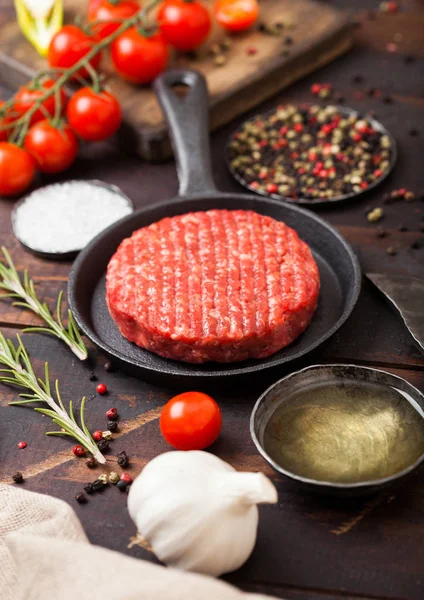 Los agricultores caseros picados crudos frescos asan hamburguesas de carne de res en una sartén con especias y hierbas y hacha de carne en un tablero de madera. Aceite, ajo y tomates . —  Fotos de Stock